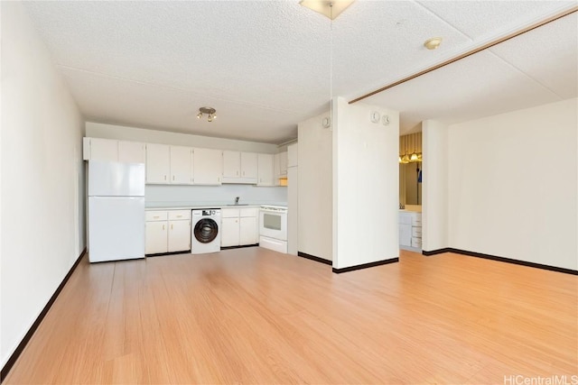 kitchen featuring white cabinetry, sink, light hardwood / wood-style flooring, white appliances, and washer / dryer