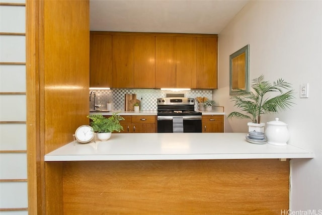 kitchen featuring backsplash, stainless steel range with electric stovetop, and sink