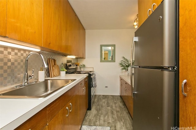 kitchen featuring sink, black electric range, light wood-type flooring, tasteful backsplash, and stainless steel refrigerator