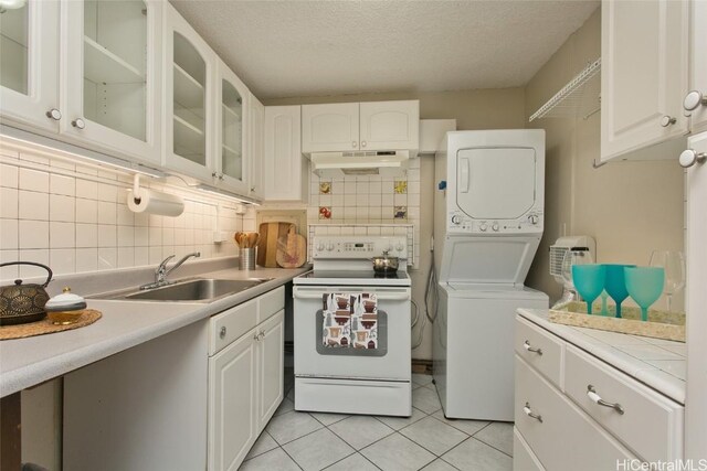 kitchen with tasteful backsplash, white cabinets, stacked washer / drying machine, and white electric stove