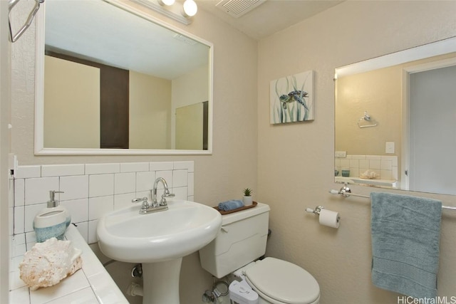 bathroom with backsplash, sink, tile walls, and toilet