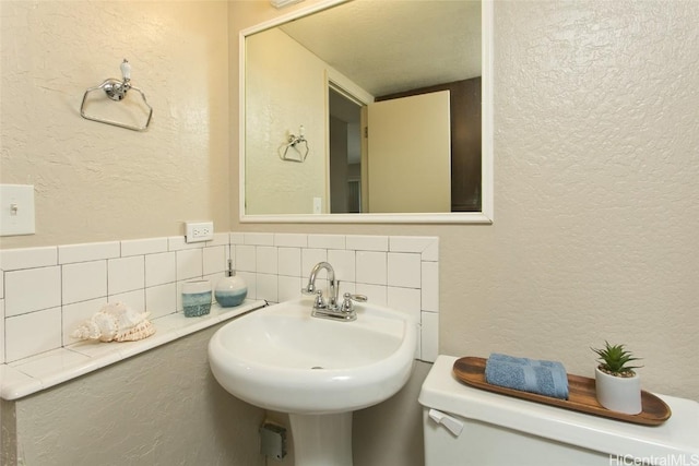 bathroom featuring sink, decorative backsplash, toilet, and a textured ceiling