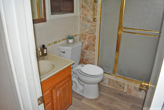 bathroom with an enclosed shower, toilet, vanity, tile walls, and hardwood / wood-style flooring