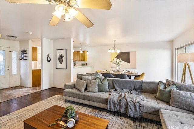 living room with ceiling fan with notable chandelier, dark hardwood / wood-style flooring, and a wealth of natural light