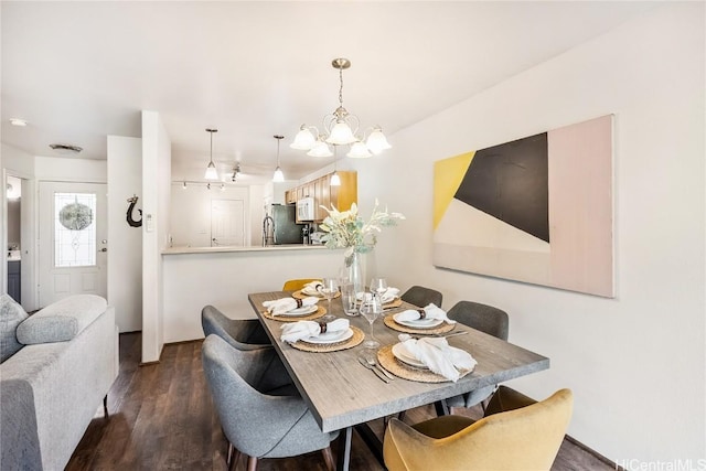 dining space featuring dark wood-type flooring and a notable chandelier