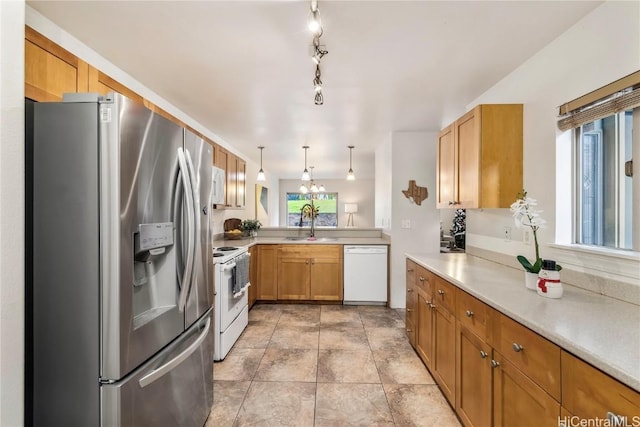 kitchen with kitchen peninsula, pendant lighting, white appliances, and sink