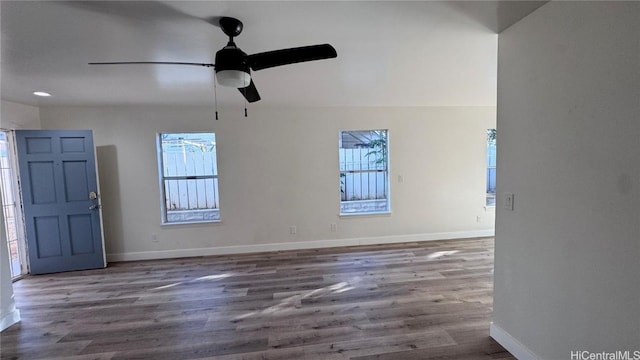 unfurnished living room featuring plenty of natural light, ceiling fan, and dark hardwood / wood-style flooring