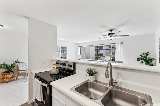 kitchen with carpet flooring, black range with electric cooktop, ceiling fan, sink, and white cabinets