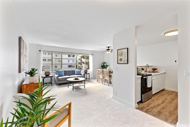 carpeted living room with ceiling fan and sink