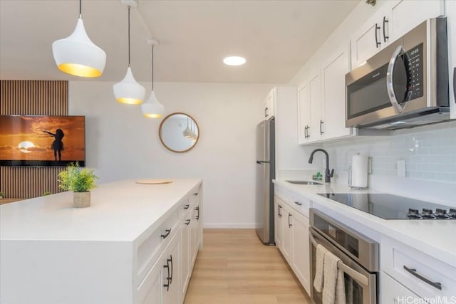 kitchen with white cabinets, pendant lighting, sink, and appliances with stainless steel finishes