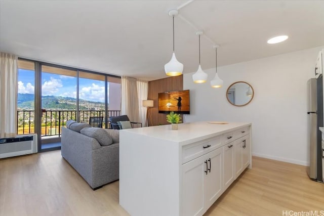 kitchen with white cabinetry, light hardwood / wood-style flooring, a mountain view, pendant lighting, and a kitchen island