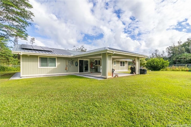 rear view of house featuring a lawn, a patio, and solar panels