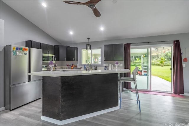 kitchen with pendant lighting, light wood-type flooring, stainless steel appliances, and vaulted ceiling