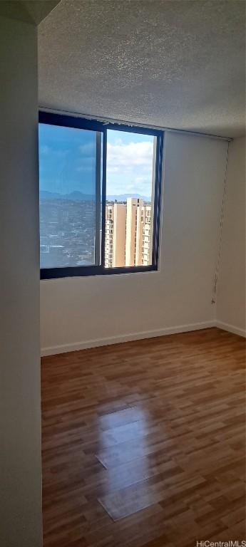 unfurnished room featuring a textured ceiling and dark wood-type flooring