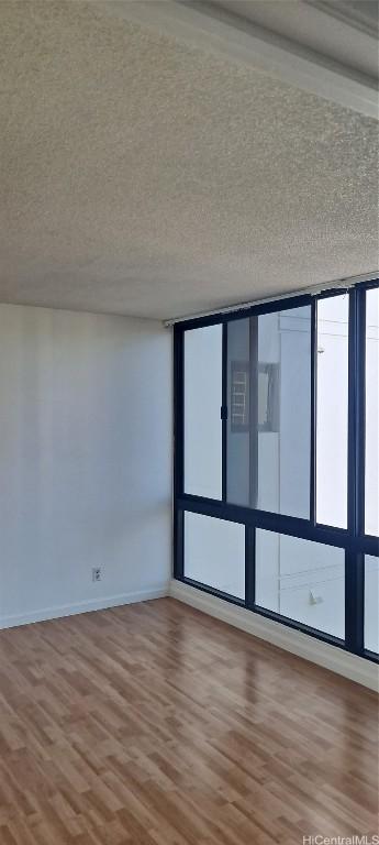 unfurnished room featuring a textured ceiling, baseboards, and wood finished floors