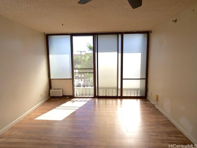 unfurnished room with ceiling fan, light hardwood / wood-style flooring, a textured ceiling, and a wall of windows