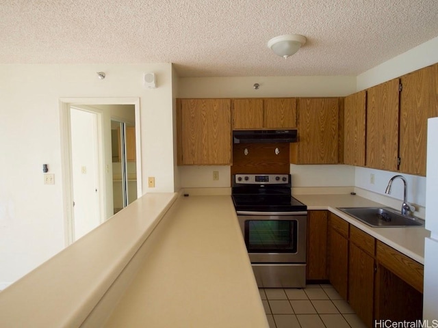 kitchen featuring stainless steel electric stove, sink, light tile patterned flooring, and a textured ceiling