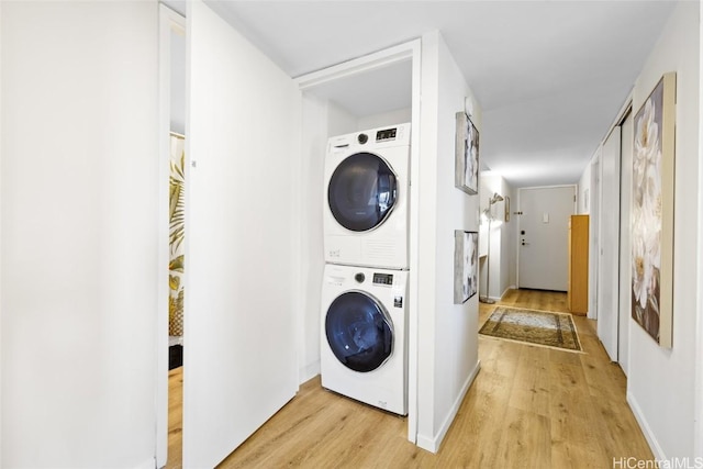 washroom featuring stacked washer and clothes dryer and light wood-type flooring