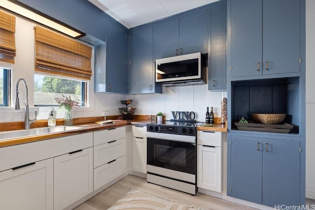 kitchen featuring blue cabinetry, electric range, butcher block countertops, and sink