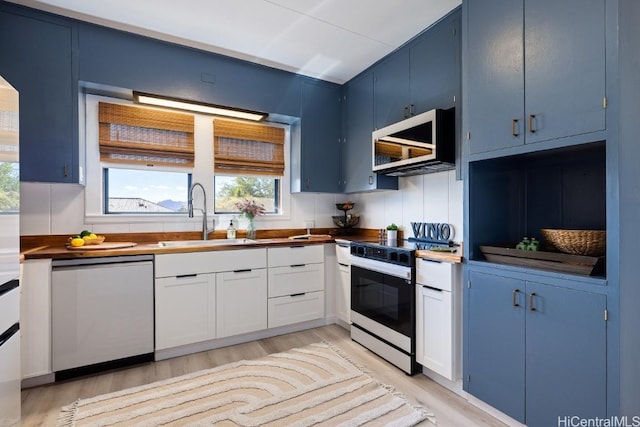 kitchen featuring blue cabinetry, appliances with stainless steel finishes, white cabinetry, and sink