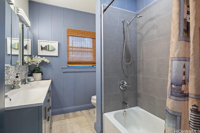 full bathroom with tiled shower / bath combo, wood-type flooring, toilet, decorative backsplash, and vanity