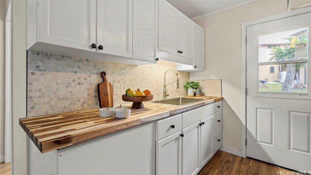 kitchen featuring wooden counters, tasteful backsplash, sink, hardwood / wood-style flooring, and white cabinetry