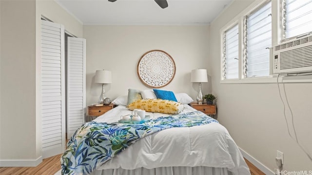 bedroom with cooling unit, light hardwood / wood-style floors, ceiling fan, and crown molding