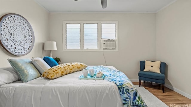 bedroom featuring ceiling fan, cooling unit, wood-type flooring, and ornamental molding