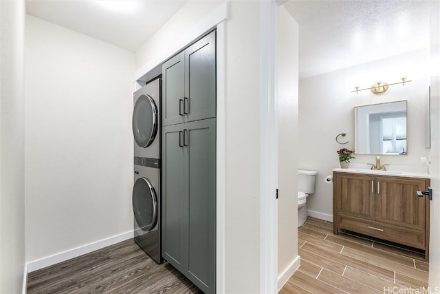 laundry room featuring sink, cabinets, and stacked washer / drying machine