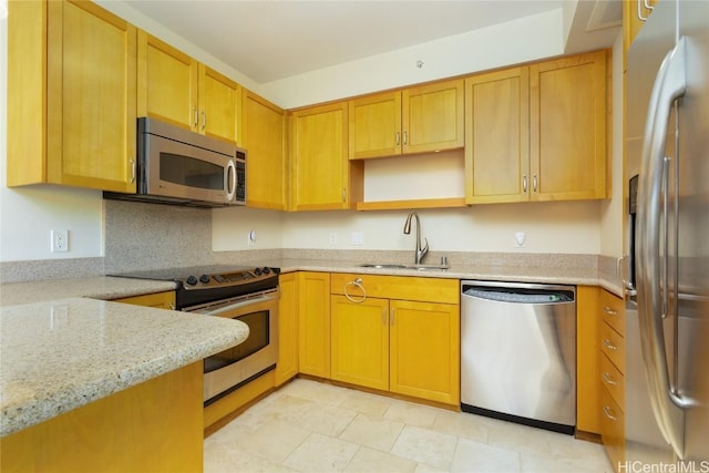 kitchen featuring backsplash, light stone counters, sink, and stainless steel appliances