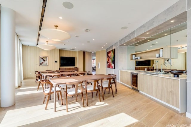 dining space with light hardwood / wood-style flooring, wine cooler, and sink