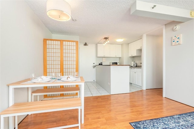 kitchen with white cabinets, light hardwood / wood-style floors, and a textured ceiling