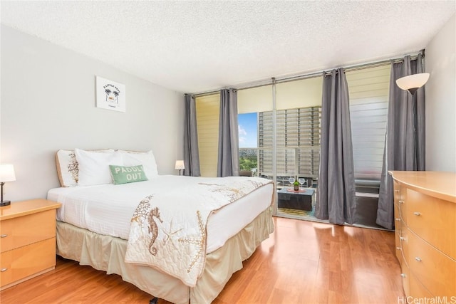 bedroom featuring access to outside, a textured ceiling, and hardwood / wood-style flooring