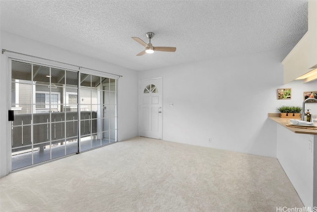 empty room with carpet, ceiling fan, and a textured ceiling