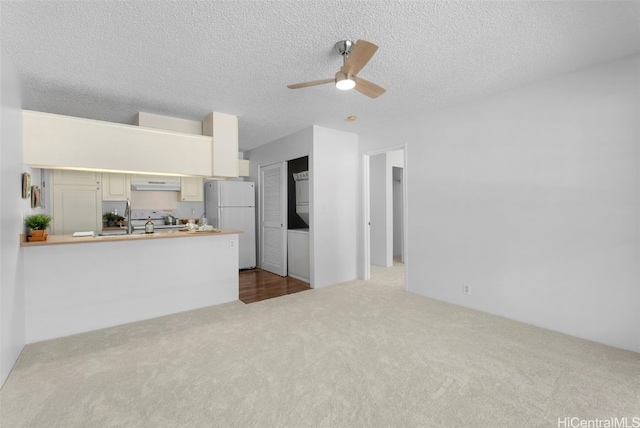 kitchen with ceiling fan, white refrigerator, extractor fan, a textured ceiling, and range