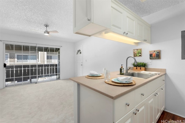 kitchen with sink, kitchen peninsula, ceiling fan, a textured ceiling, and white cabinetry