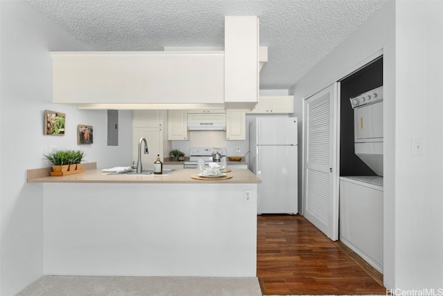 kitchen featuring kitchen peninsula, stacked washer / dryer, white appliances, and sink