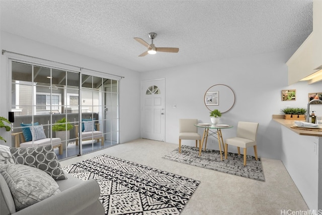 living room with carpet flooring, ceiling fan, sink, and a textured ceiling