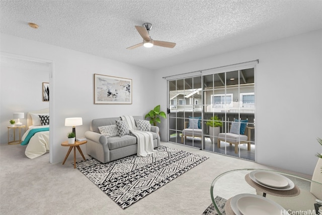 living room featuring a textured ceiling, carpet floors, and ceiling fan