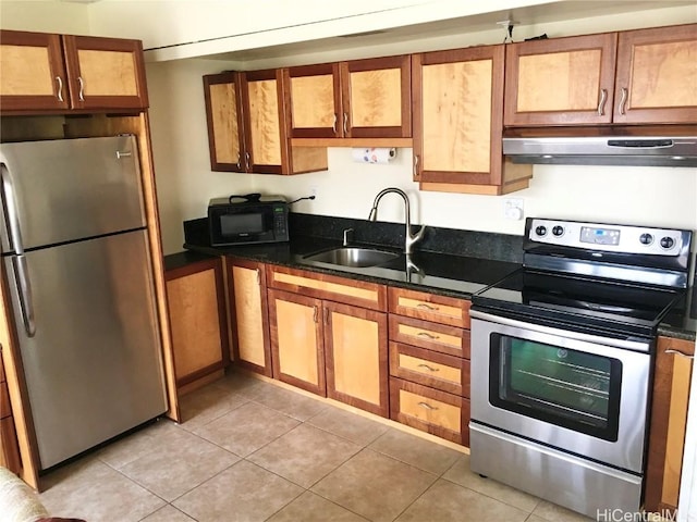 kitchen featuring light tile patterned floors, stainless steel appliances, dark stone countertops, and sink