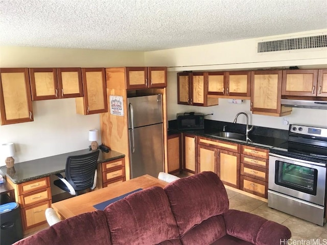 kitchen featuring sink, light tile patterned floors, stainless steel appliances, and a textured ceiling