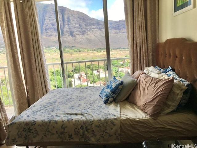 bedroom with multiple windows, a mountain view, and access to exterior