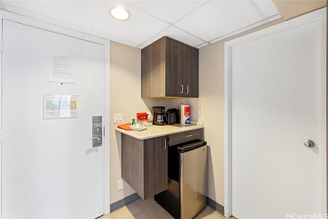 kitchen featuring dark brown cabinets, a paneled ceiling, and light tile patterned flooring