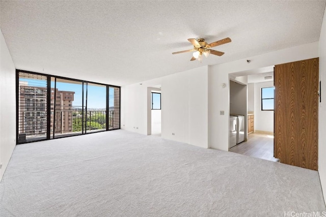 carpeted spare room featuring ceiling fan, a textured ceiling, a wealth of natural light, and washing machine and clothes dryer