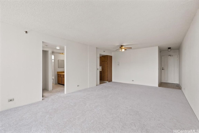 spare room with a textured ceiling, ceiling fan, and light carpet