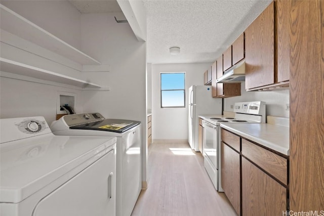 washroom with washing machine and dryer, light hardwood / wood-style floors, and a textured ceiling