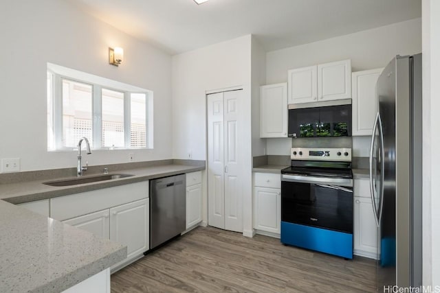 kitchen with hardwood / wood-style flooring, appliances with stainless steel finishes, sink, and white cabinets