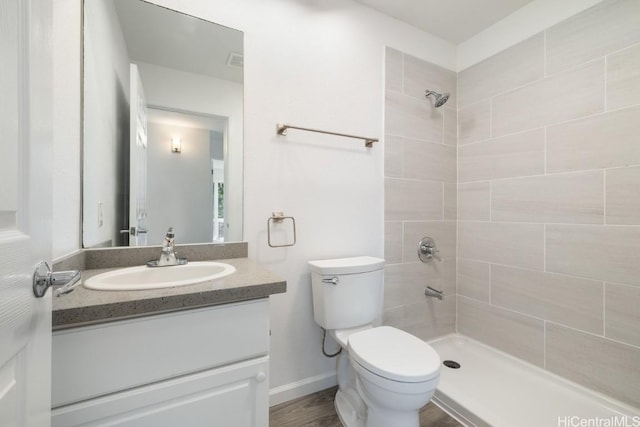 bathroom featuring tiled shower, vanity, and toilet