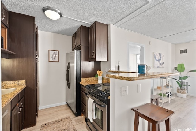 kitchen featuring light stone countertops, dark brown cabinets, and appliances with stainless steel finishes