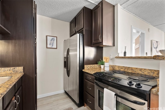 kitchen featuring dark brown cabinetry, light stone counters, light hardwood / wood-style flooring, a textured ceiling, and appliances with stainless steel finishes